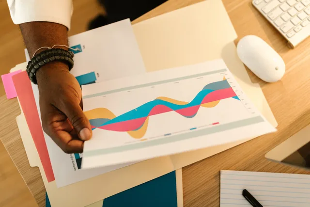 A person's hand holds a printed business graph paper on a desk with office supplies. Ecommerce conversion benchmark research: an audit method